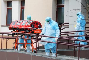 Медыцынскія работнікі ў ахоўных касцюмах перамяшчаюць капсулу з жанчынай унутры. Мінск, 12 сакавіка 2020 года. REUTERS / Васіль Федасенка