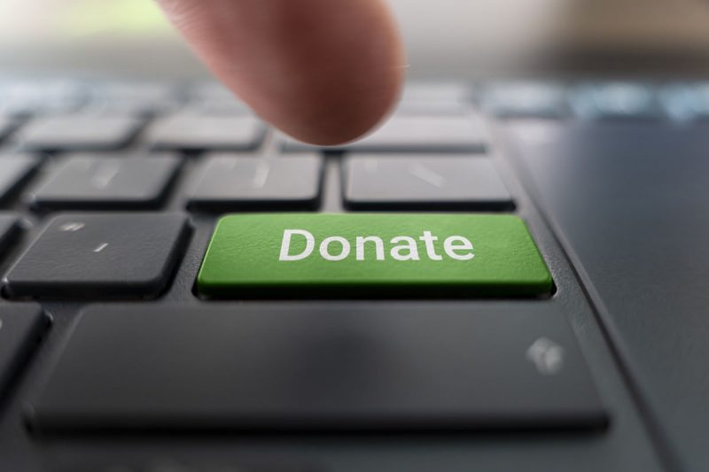 Донаты в BYSOL - уголовное дело за донаты. Red donate button on the keyboard close-up. blurred in motion background.